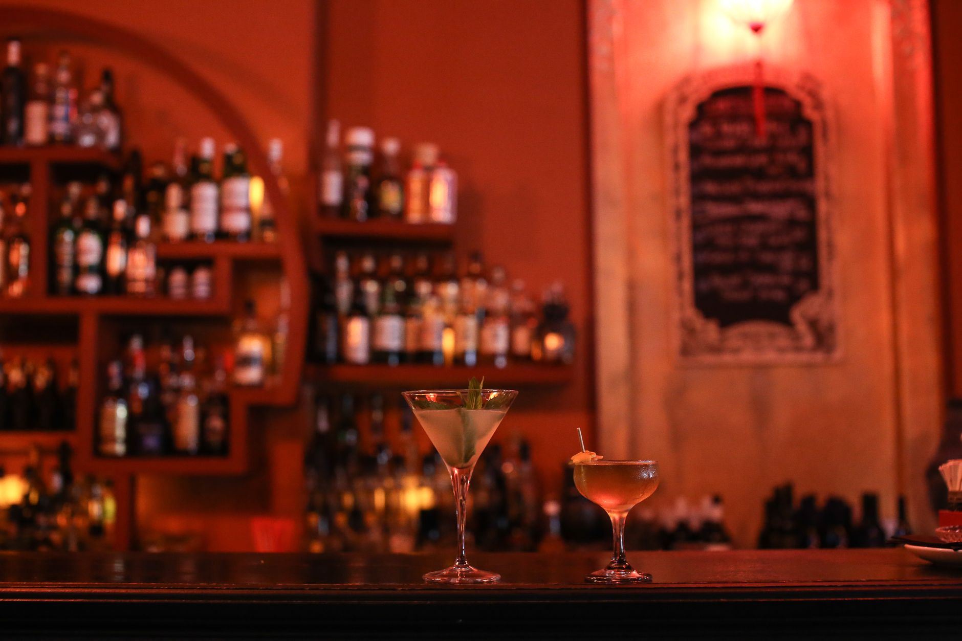 Elegant cocktails on a bar counter in a cozy nightlife setting with ambient lighting.
